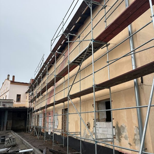 Fasádní lešení po celé délce dlouhé budovy během zateplování