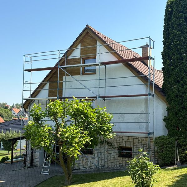 Fasádní lešení na rodinném domě se světlou fasádou